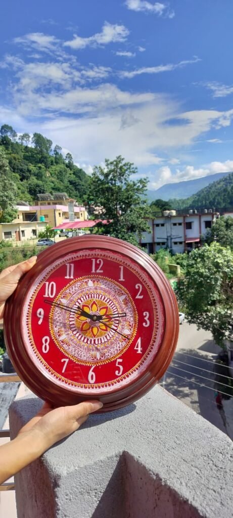 यह एक वाल हैंगिंग घड़ी है जिसमें हमने उत्तराखंड की पारंपरिक कला जिसे एपन आर्ट कहते है उसे बनाया है